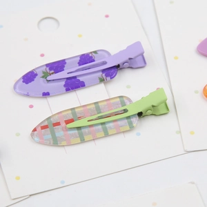 Détail de pinces à cheveux en acétate avec motifs de raisin et design à carreaux colorés