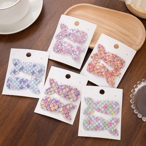 Flat lay of colorful sequined mermaid tail hair clips on display cards over wooden table