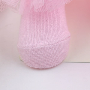 Close-up of baby pink knitted infant socks featuring delicate layered lace ruffle trim