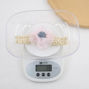 Detail showing an ultra-lightweight infant floral headband weighing only 7.9g on a digital scale