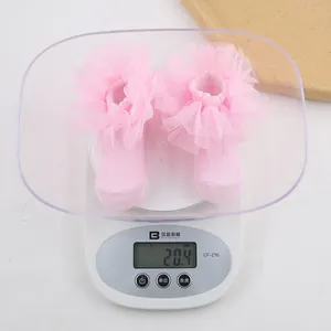 Pink lace baby sock with mesh ruffles weighing 20.4g on a digital scale for accuracy