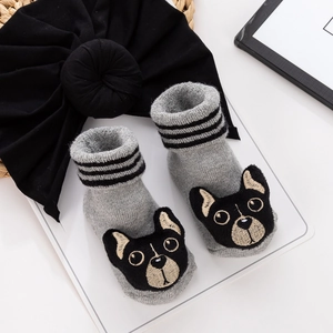 Close-up of grey knit baby socks with bulldog pattern and black knotted turban hat