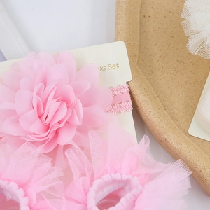 Close-up of pink chiffon flower headband and lace socks set for baby photo props