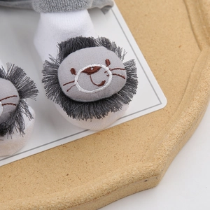 Close-up of cotton baby socks featuring a cute 3D lion character with grey fringe mane