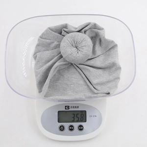 Detailed view of lightweight 35.8g grey knitted baby donut hat on a digital scale