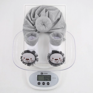 Detail shot of baby turban hat and lion socks gift set weighing 90.4g on a scale