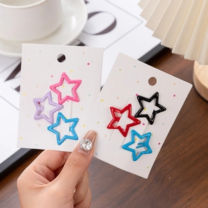 Detailed view of colorful star-shaped hair clips displayed on a white card with polka dots