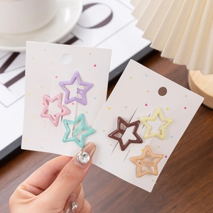 Close-up of star shaped hair clips in macaron colors displayed on a card with cute props
