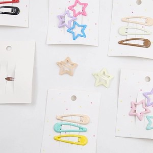 Close-up of star-shaped and teardrop metal hair clips in colorful macaque shades