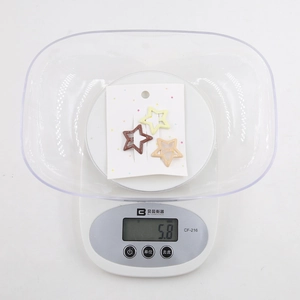 Detailed view of three star hair clips in yellow, coffee, and beige on a scale showing 5.8g