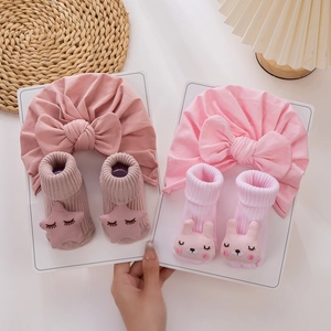Gros plan sur bonnet turban rose pour bébé avec nœud et chaussettes antidérapantes 3D