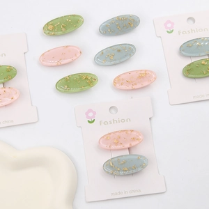 Detailansicht der Haarklammern in Rosa, Blau und Grün mit eleganten Goldflocken-Inlays