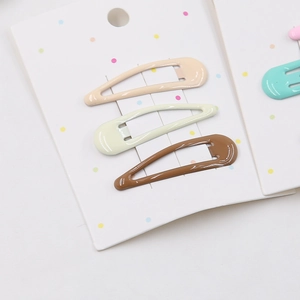 Close-up of three teardrop-shaped BB clips in cream, yellow, and brown on card
