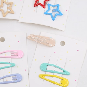Detail of colorful star and teardrop metal hair clips on display card with glossy finish