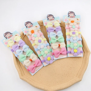 Détail des élastiques à cheveux fleurs et nœuds aux couleurs pastel sur carte décorative