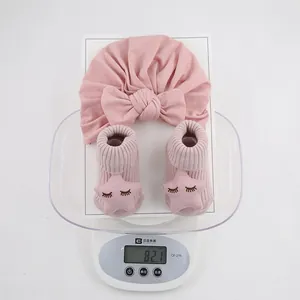Ensemble bonnet et chaussettes roses pour bébé pesant 82,1g sur une balance
