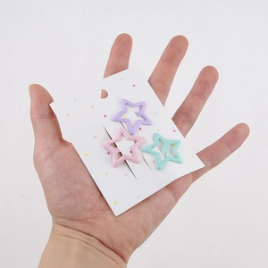 Macro view of three colorful star hair clips in lavender, pink, and mint green on card