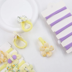 Détail d'un chouchou jaune à fleurs et de bandeaux violets sur un plateau blanc
