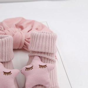 Gros plan sur les chaussettes en tricot rose et le bandeau à nœud pour bébé avec étoiles