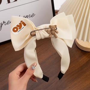Detail eines cremefarbenen Chiffon-Haarreifs mit 3D-Bär und Metallstift-Akzent
