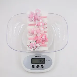 Vue détaillée de cinq chouchous fleurs roses en tissu pesant 14,2g sur une balance