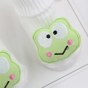 Détail de chaussette blanche pour bébé en coton avec broderie de grenouille verte