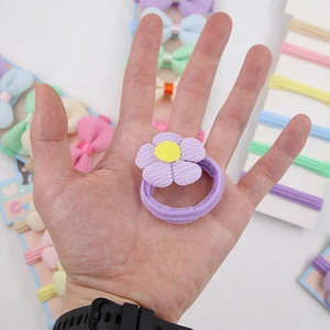 Vue détaillée d'un élastique à cheveux fleur violette avec pétales en tissu doux