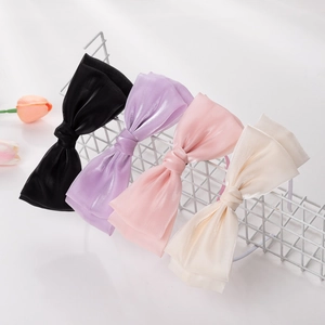 Détail de serre-têtes en maille à nœuds papillon en noir, violet, rose et blanc crème