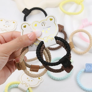 Close-up of colorful braided elastic hair bands with leather smiley face tags on card