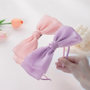 Détail de grands serre-têtes à nœuds en organza rose et violet avec texture plissée fine