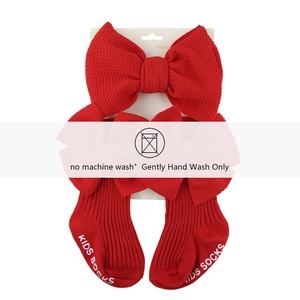 Détail de chaussettes bébé en maille gaufrée rouge avec bandeau à nœud assorti