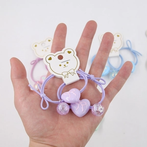 Detail of purple heart pendant hair tie with glitter bead and bear shaped card packaging