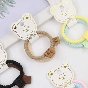 Detail of woven elastic hair ties with Hand Made leather tags on cute bear card