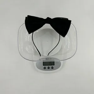 Détail macro montrant le poids du serre-tête noir à double nœud papillon à 15,1g