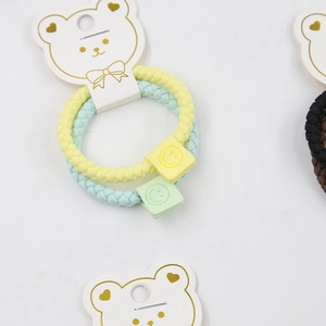 Macro detail of elastic woven hair ties with smile charms on bear card packaging