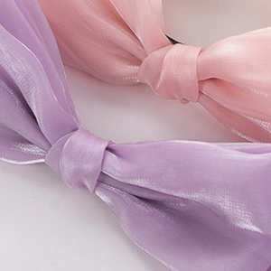 Vue macro d'un serre-tête nœud en organza scintillant rose et violet au fini nacré