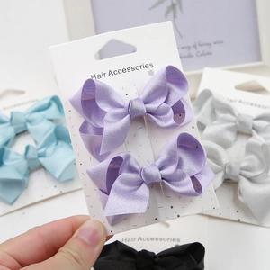 Detail view of two purple satin bow hair clips on a card display for children