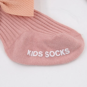 Gros plan de chaussettes roses en coton avec nœud et semelle antidérapante en silicone