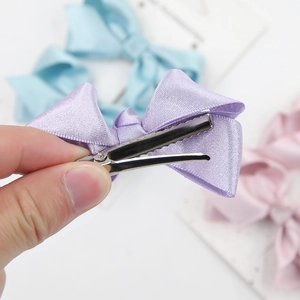 Detail of satin fabric texture and metal alligator clip on colorful bow hairpins