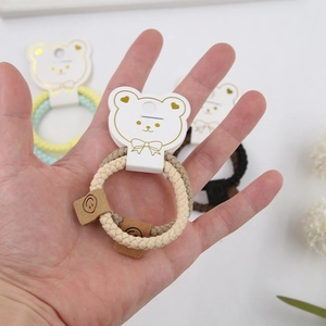 Detail of woven elastic hair ties with smiley leather tag and cute bear card holder