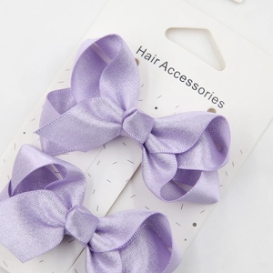 Detailed shot of two lavender satin ribbon bow hair clips on a white display card