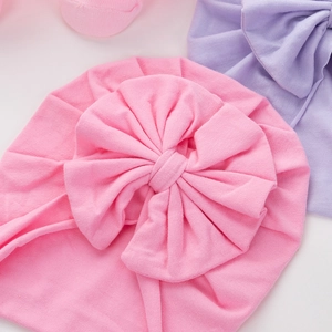 Close-up of pink and purple newborn cotton turban hats with large soft knit bows