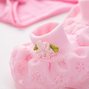 Detailed macro view of pink newborn baby socks with 3D floral lace and pearl embellishments