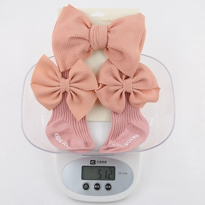 Ensemble bandeau et chaussettes bébé rose corail côtelé avec nœuds sur une balance