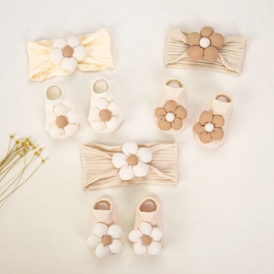 Gedetailleerd overzicht van drie babyhoofdbanden met bloemen en sokken in crème en beige