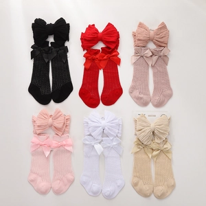 Flat lay of six pairs of baby mesh socks and matching large bow headbands in soft colors