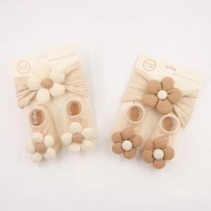 Detailoverzicht van de gebreide hoofdband en sokkenset voor baby's met 3D-bloemen