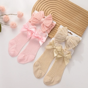 Detail showing pink and beige infant hollow knit socks with silk bows and headband set