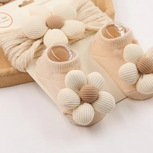 Detailweergave van baby hoofdband en sokken set in crème katoen met bloemaccenten