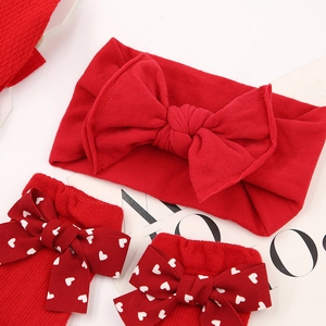 Detail view of red baby headband with large bow and matching heart-pattern socks